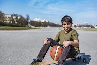 Portrait of smiling boy with longboard and basketball outdoors - DIGF04156