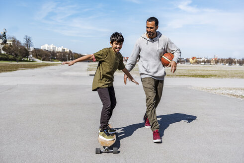 Vater und Sohn mit Longboard und Basketball im Freien - DIGF04158