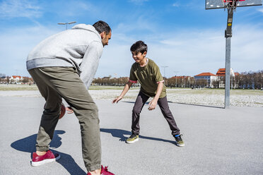 Vater und Sohn spielen Basketball auf einem Platz im Freien - DIGF04162