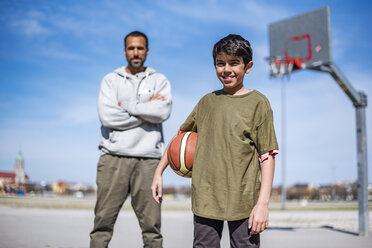 Porträt eines Jungen mit Vater auf einem Basketballplatz im Freien - DIGF04165