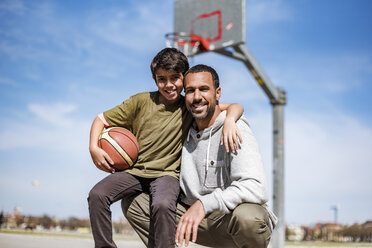 Portrait of happy father and son with basketball outdoors - DIGF04167