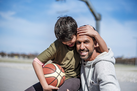 Porträt von glücklichem Vater und Sohn mit Basketball im Freien, lizenzfreies Stockfoto