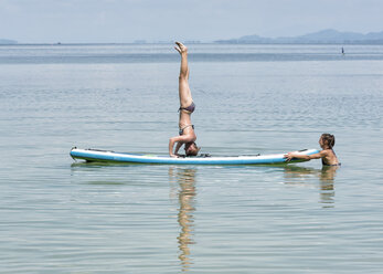 Thailand, Krabi, Lao Liang, woman doing a headstand on SUP Board in the ocean - ALRF01161