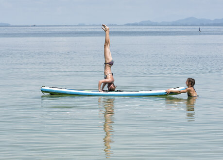 Thailand, Krabi, Lao Liang, Frau macht einen Kopfstand auf SUP Board im Meer - ALRF01161