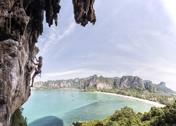 Thailand, Krabi, Thaiwand, Frau klettert in Felswand über dem Meer - ALRF01197