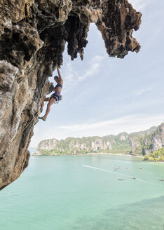 Thailand, Krabi, Thaiwand, Frau klettert in Felswand über dem Meer - ALRF01198