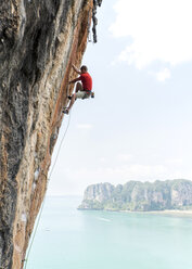 Thailand, Krabi, Thaiwand, Mann klettert in Felswand über dem Meer - ALRF01201