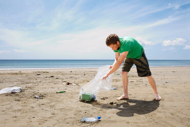 Junger Mann beim Müllsammeln am Strand - CUF00927