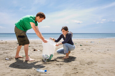 Young couple collecting garbage on beach - CUF00928