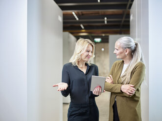 Zwei Geschäftsfrauen teilen sich ein Tablet im Büro - CVF00352