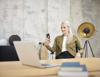 Businesswoman looking at cell phone in office - CVF00357