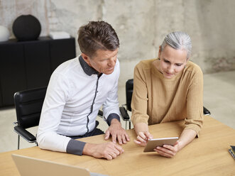 Geschäftsmann und Geschäftsfrau teilen sich ein Tablet im Büro - CVF00360