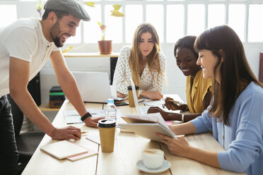 Lächelnde Kollegen arbeiten zusammen am Schreibtisch im Büro - EBSF02499