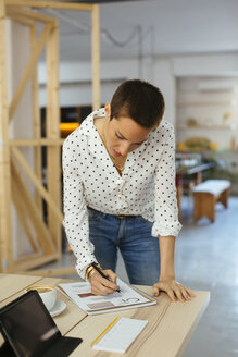 Woman working on draft at desk in office - EBSF02520