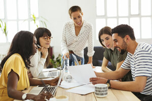 Lächelnde Kollegen arbeiten zusammen am Schreibtisch im Büro - EBSF02530