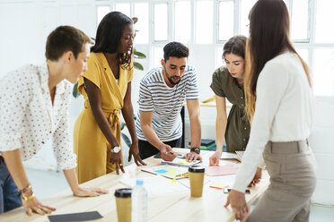 Kollegen arbeiten zusammen am Schreibtisch im Büro und besprechen Papiere - EBSF02539