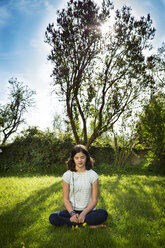 Girl sitting on meadow listening music with headphones - LVF06938