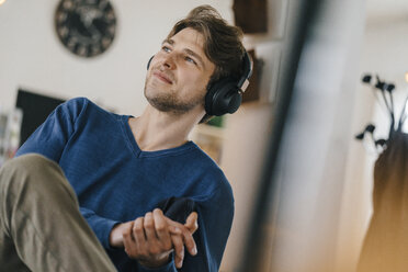 Smiling man in a cafe wearing headphones - KNSF03846