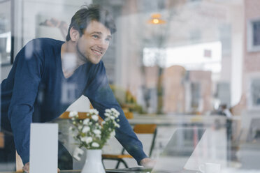 Smiling man in a cafe looking out of window - KNSF03849