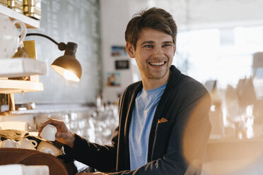 Smiling man in a cafe holding cup - KNSF03852