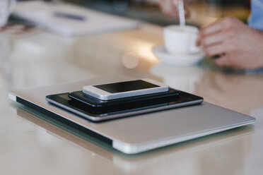 Stack of mobile devices and man with coffee - KNSF03856