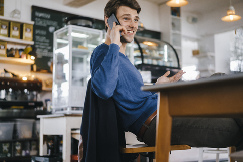 Lächelnder Mann in einem Café mit Mobiltelefon, lizenzfreies Stockfoto