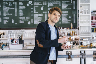 Porträt eines lächelnden Mannes mit einer Tasse Kaffee in einem Kaffeehaus - KNSF03882