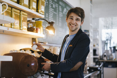 Portrait of smiling man in a cafe holding cup - KNSF03885