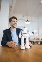 Laughing man with robot on table - KNSF03898