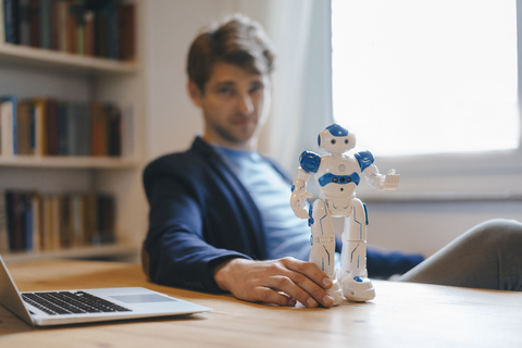 Man sitting at table with robot stock photo