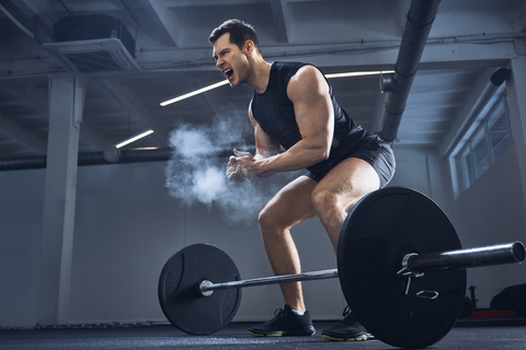 Motivierter Gewichtheber klatscht vor dem Hanteltraining im Fitnessstudio in die Hände, lizenzfreies Stockfoto