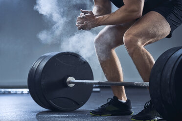 Nahaufnahme eines Mannes, der vor dem Hanteltraining im Fitnessstudio in die Hände klatscht - BSZF00315