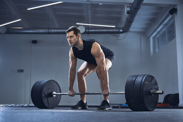 Mann bei einer Langhantelübung im Fitnessstudio während eines Krafttrainings - BSZF00318