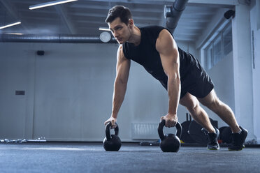 Man doing pushups on kettlebells at gym - BSZF00320