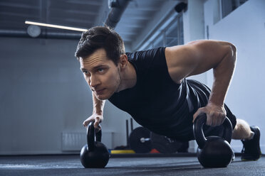 Man doing pushups on kettlebells at gym - BSZF00321