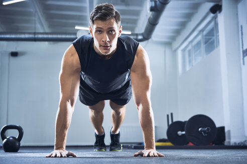 Athletischer Mann macht Liegestütze im Fitnessstudio - BSZF00323