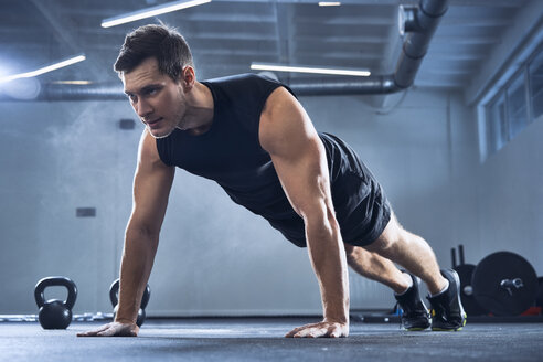 Athletic man doing pushups exercise at gym - BSZF00324