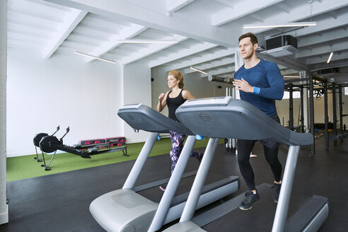 Mann und Frau laufen auf dem Laufband im Fitnessstudio - BSZF00332