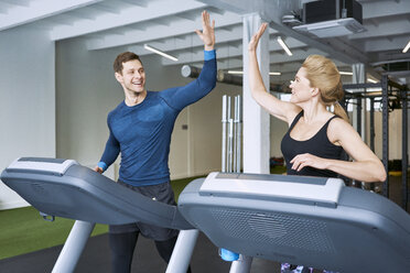 Glücklicher Mann und Frau tun hohe fünf während Laufband Übung im Fitnessstudio - BSZF00334