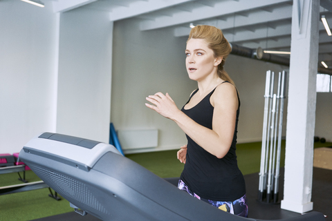 Woman running on treadmill at gym stock photo