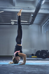 Woman doing headstand yoga exercise at gym - BSZF00358