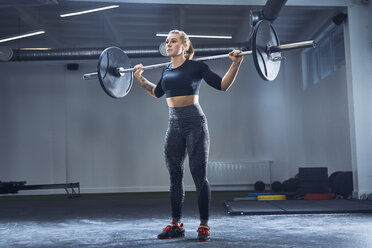 Frau übt Langhantelhocke im Fitnessstudio - BSZF00363