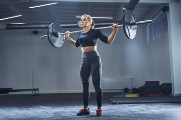 Woman practicing barbell squat at gym - BSZF00363