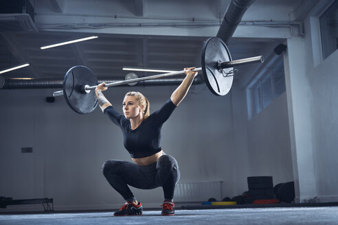 Woman doing overhead squat exercise at gym - BSZF00364