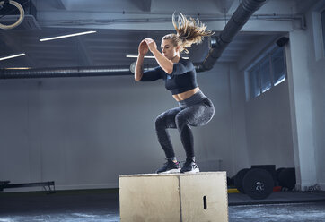 Sportliche Frau macht Boxsacksprung-Übung im Fitnessstudio - BSZF00374