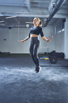 Sportliche Frau, die mit einem Springseil im Fitnessstudio springt - BSZF00376