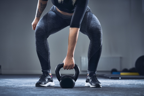 Nahaufnahme einer sportlichen Frau, die mit einer Kettlebell im Fitnessstudio trainiert, lizenzfreies Stockfoto