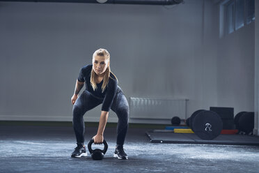 Frau trainiert mit Kettlebell im Fitnessstudio - BSZF00379