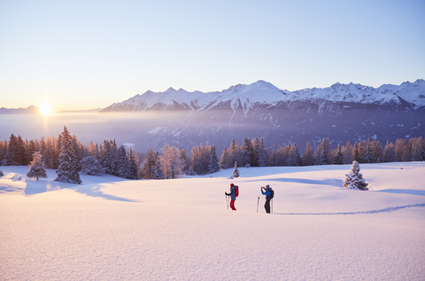 Österreich, Tirol, Paar beim Sonnenaufgang auf Schneeschuhen, lizenzfreies Stockfoto