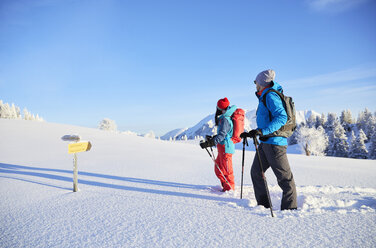 Österreich, Tirol, Paar beim Schneeschuhwandern, stehend vor einem Wegweiser - CVF00416